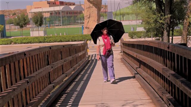 Woman walking on wooden bridge with umbrella
