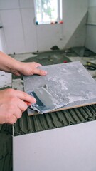 Hands placing tile on adhesive