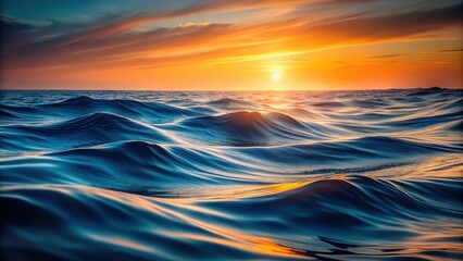 Obraz premium Deep blue ocean waves gently undulating on a dark grey background with orange hues in the distance