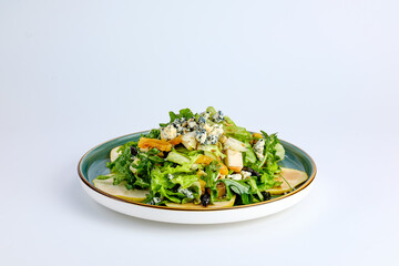 A vibrant green salad featuring fresh lettuce, sliced apples, blue cheese crumbles, and nuts, served on a ceramic plate