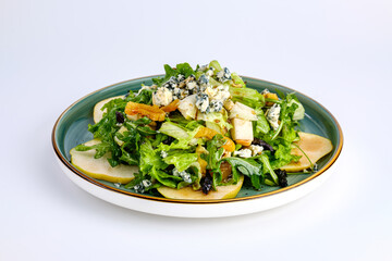 A vibrant green salad featuring fresh lettuce, sliced apples, blue cheese crumbles, and nuts, served on a ceramic plate