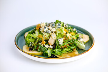 A vibrant green salad featuring fresh lettuce, sliced apples, blue cheese crumbles, and nuts, served on a ceramic plate