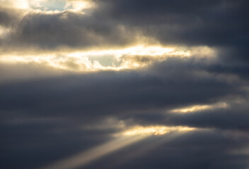 Sunlight rays breaking through dark storm clouds
