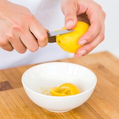 Hands zesting a lemon over a bowl