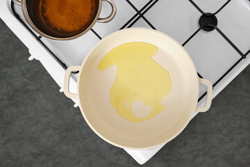 Cooking oil is poured into a frying pan on a stovetop for meal preparation