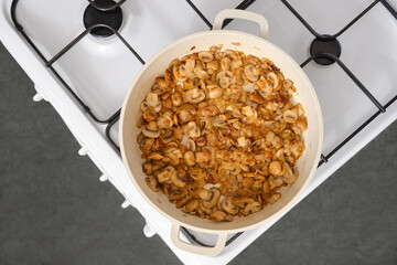 Top view of mushrooms fried in oil in a frying pan on the stove in the kitchen