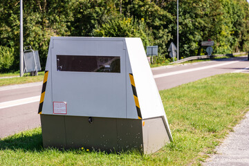 A mobile road safety camera is placed on the side of a busy road for traffic speed enforcement in a small town in France.