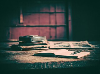 Vintage still life on a wooden table, with books, a camera, newspaper, and notepad