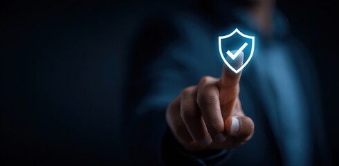 Hand touches glowing shield with checkmark on a dark blue background. Conceptual tech image illustrating digital safety, security, protection, and verification