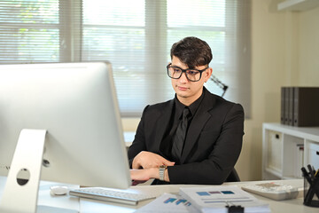 Fototapeta premium Professional businessman with glasses focused on screen while analyzing financial data