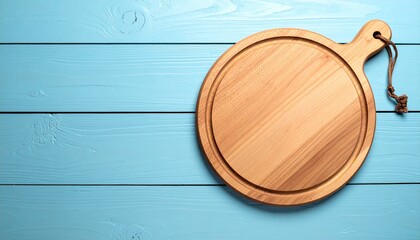 Round wooden cutting board with rope handle on blue plank surface