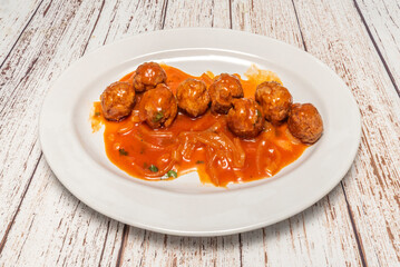 Homemade mixed-meat meatballs with a spiced natural tomato sauce, served in a clay pot with fresh parsley and bread for dipping.