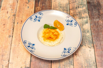 Creamy traditional rice pudding with cinnamon sticks and lemon peel, sprinkled with ground cinnamon and presented in a rustic clay pot