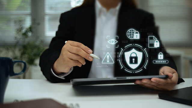 Businesswoman using digital tablet with holographic cybersecurity icons, data protection concept