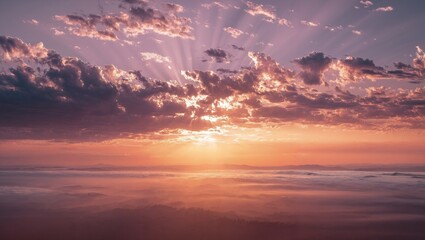 Fototapeta premium Sunrise over misty landscape with rays of sunlight breaking through scattered clouds creating warm orange and purple hues in the early morning sky above hills