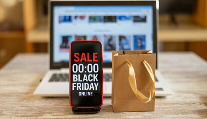 Red smartphone showing black friday online sale countdown and shopping bag on desk with laptop in background represent online shopping and discounts during black friday cyber monday sales