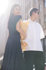 Naklejka premium Young couple dressed stylishly in an urban setting enjoying a sunny day together.