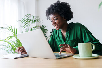 Happy businesswoman with laptop writing on note pad