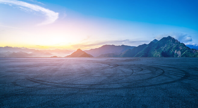 Empty asphalt race track ground with car tire skid marks and beautiful mountain natural landscape at sunrise