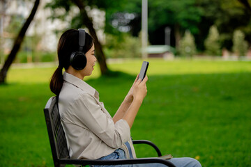 Happy woman sitting outdoors in nature under a tree, reading a book peacefully, enjoying summer relaxation, wellness, learning, and tranquility.
