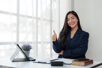 Smiling businesswoman gesturing thumbs up at office desk