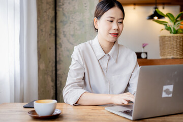 Confident businesswoman working at desk with computer in office, smiling while focusing on tasks, symbolizing success, motivation, persistence, and professionalism.
