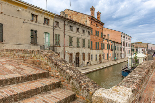 Comacchio, Italy, 08 24 2025, historic canal view with old colorful houses, brick bridge and reflections in the water, capturing the charm of the little Venice of Emilia-Romagna.