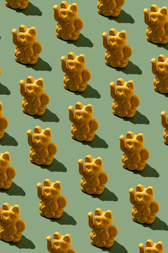 Yellow maneki neko figurines in seamless pattern on green background