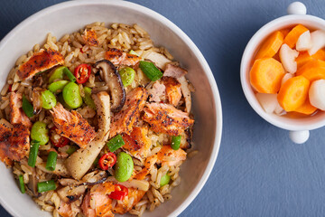 Salmon fried rice with mushrooms, red peppers and edamame, served with side dishes.