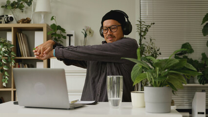 Asian man is stretching his body after working at home.