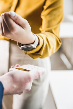 Businesswoman paying with smart watch on credit card reader