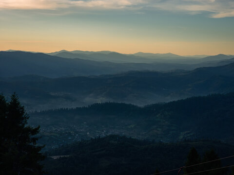 A peaceful twilight view of layered mountain ranges with dense pine forests, ideal for travel ads, wellness campaigns, and nature-inspired branding