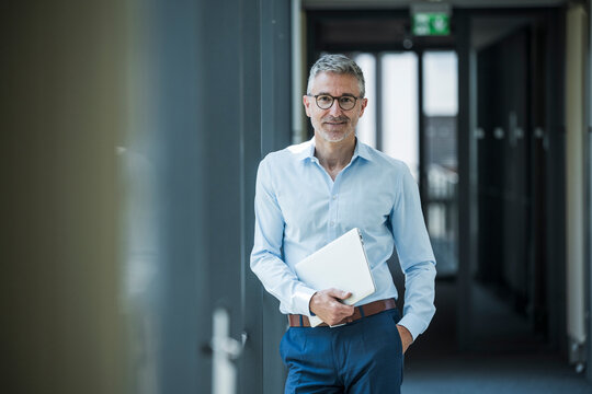Business professional with notebook standing in modern office corridor
