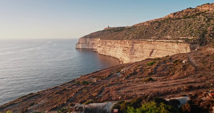 Malta: Dingli Cliffs in golden sunset light, showcasing the rugged coastline hills and vast Mediterranean Sea. Low angle drone flight footage