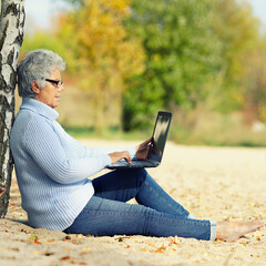 senior woman with laptop at the beach 