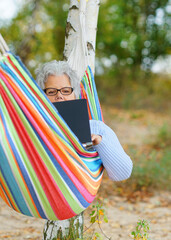 Autumn Bliss: Senior Relaxing with a Laptop by the Lake