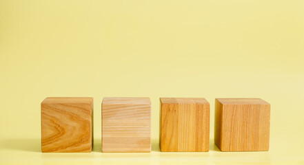 a minimal mockup of four wooden cubes arranged on a yellow background	