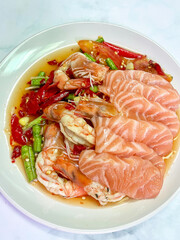 Fresh salmon sashimi and cooked shrimp in spicy chili sauce with green bean and tomato, appetizing seafood plate with savory and tangy flavor