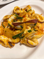 Stir fried squid with onion and chili sauce, savory and spicy seafood dish with herbs and eggy texture