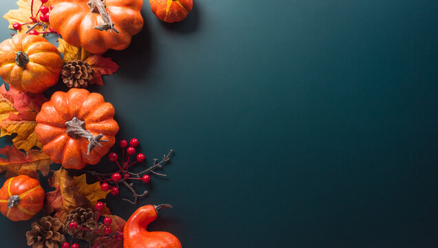 Thanksgiving and Autumn decoration concept made from autumn leaves and pumpkin on dark background. Flat lay, top view with copy space.