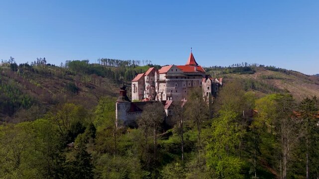 Majestic Pernstein Castle stands high on a rock formation above Nedvedice, captured by drone, showcasing its stunning Gothic and Renaissance architecture in South Moravia, Czechia.