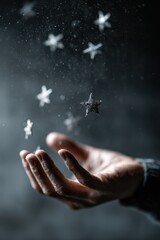 A hand reaching for glittering stars floating against a dark atmospheric background