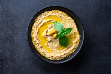 A traditional dish or appetizer hummus or baba ghanoush on black  background
