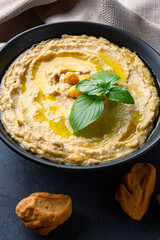 A traditional dish or appetizer hummus or baba ghanoush on black  background