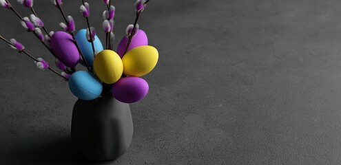 Colorful Easter eggs in a dark vase with pussy willow branches