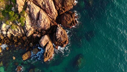 High-angle view of rocky coastline meeting turquoise water