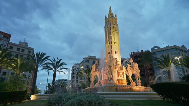 Alicante, Spain - May 19, 2025: Time lapse of people moving through the Plaza de los Luceros Fountain at blue hour