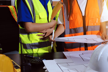 Closeup of team of industrial engineers meeting analyze machinery blueprints consult project on...