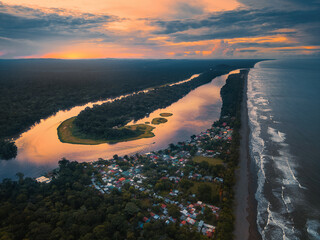 Sunset aerial view of Tortuguero, Costa Rica with river meander, jungle, ocean, and warm colors