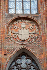 Papal coat of arms of John Paul II on red brick facade of gothic Torun Cathedral, Torun, Poland